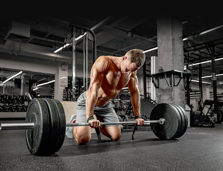 Man bending over a barbell at the gym.
