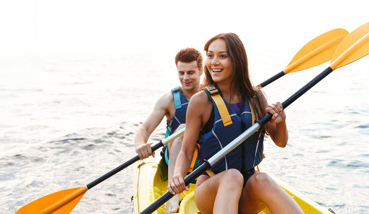 A smiling man and woman canoeing together in the water.