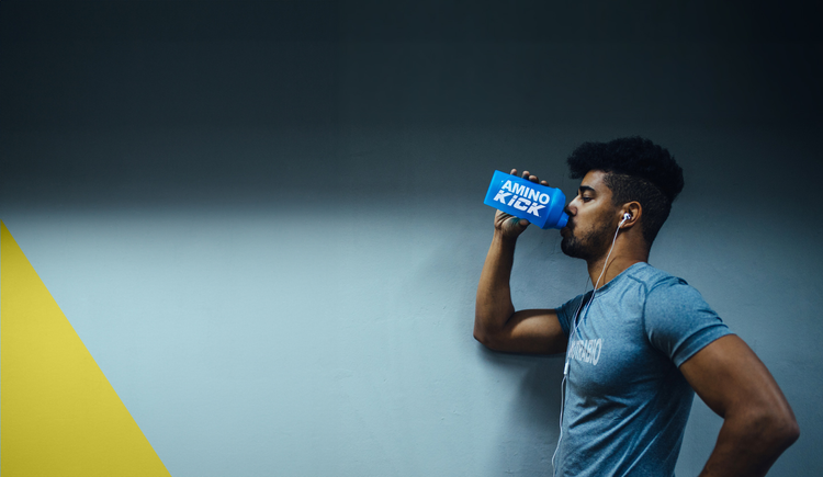 Man in gym clothing consuming a post workout supplement beverage.
