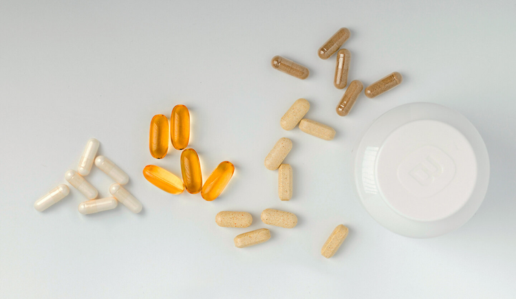 Pills and capsules scatered around a jar.