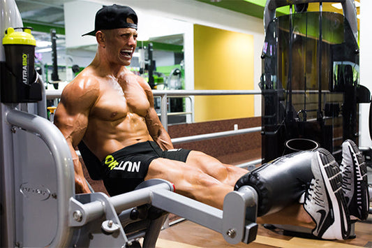 Man working out in the gym wearing black NutraBio shorts and a baseball cap.