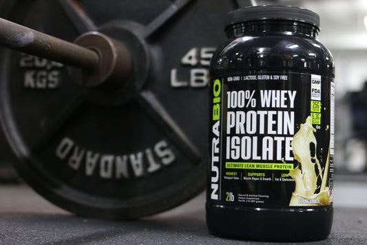 Bottle of NutraBIo's Whey Protein Isolate on a gym floor with a barbell behind it