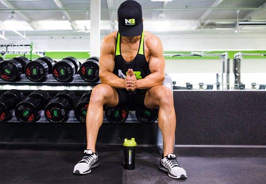 Man with a NutraBio baseball capp on sitting on a bench in a gym