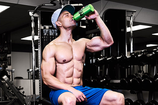 Man sitting and drinking from a green stainless steel water bottle with the NutraBio logo on it