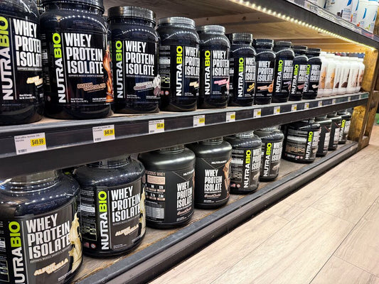 NutraBio whey protein isolate tubs displayed on retail store shelves in multiple flavors and sizes.