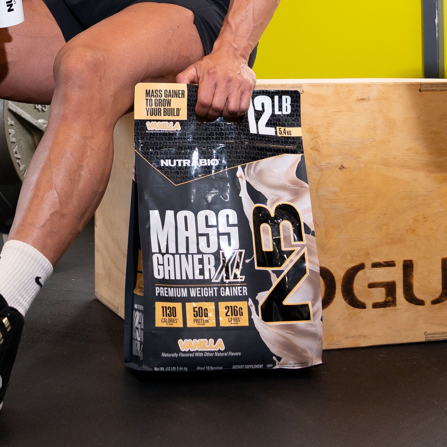 Person holding a Nutreco Mass Gainer XL package with a gym background