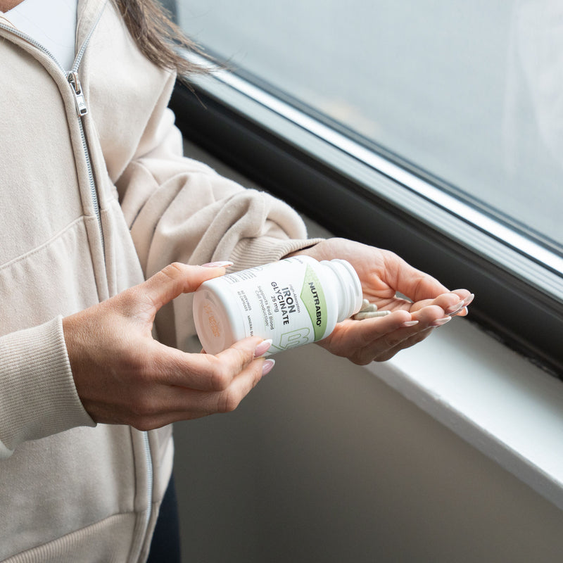 Female holding Iron Glycinate by Nutrabio by window. 