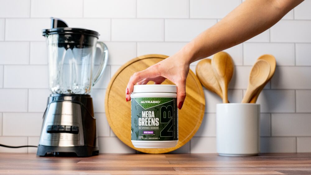 Female holding Nutrabio mega greens in the kitchen