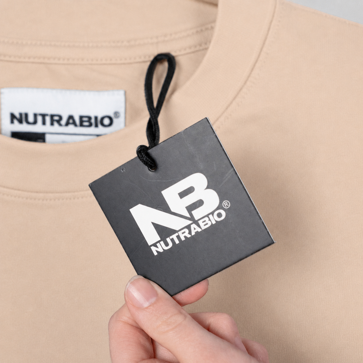 NUTRABIO tag on a beige garment with a hand holding a black card displaying the brand logo.